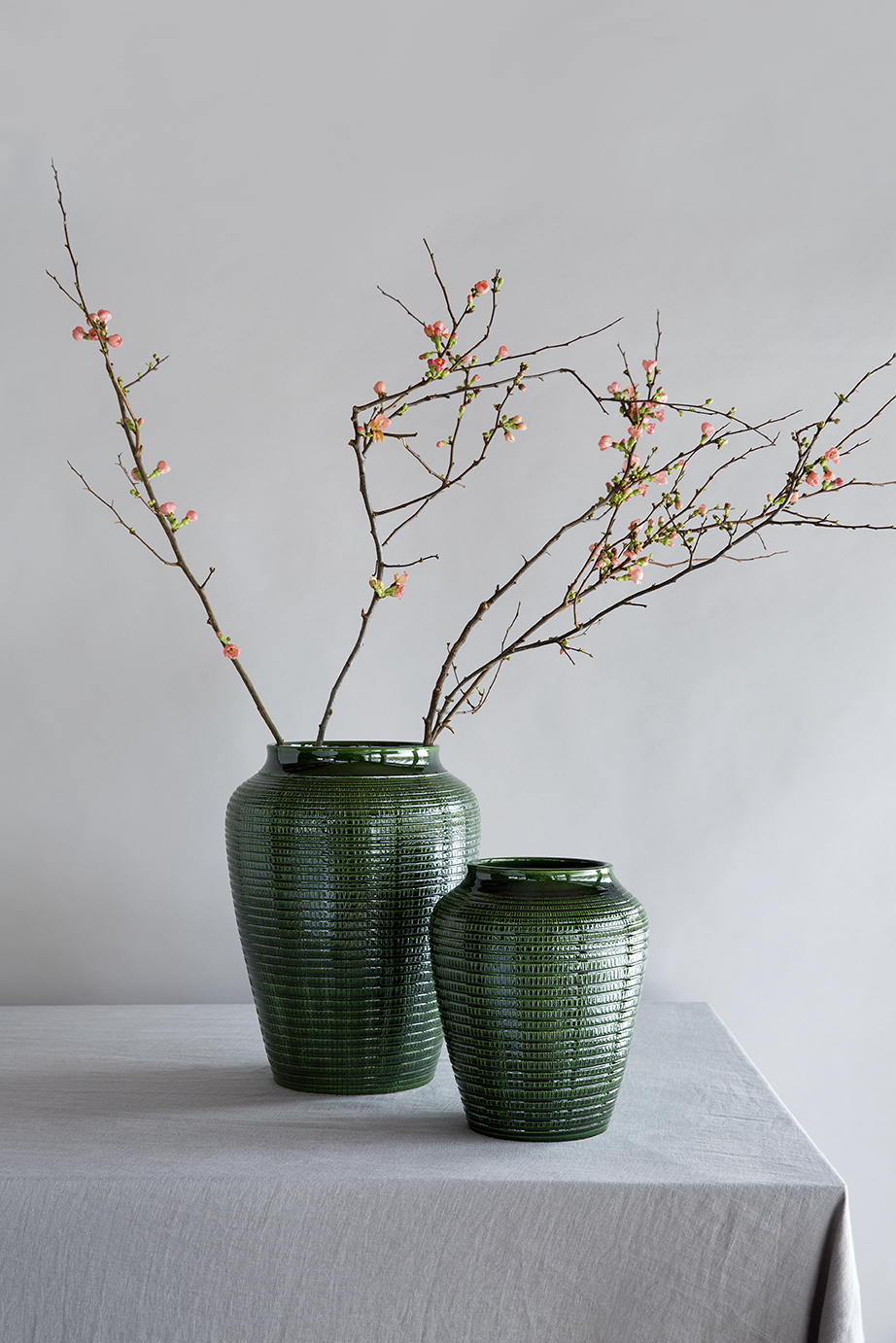 Large and small green glazed vases with pattern on a table