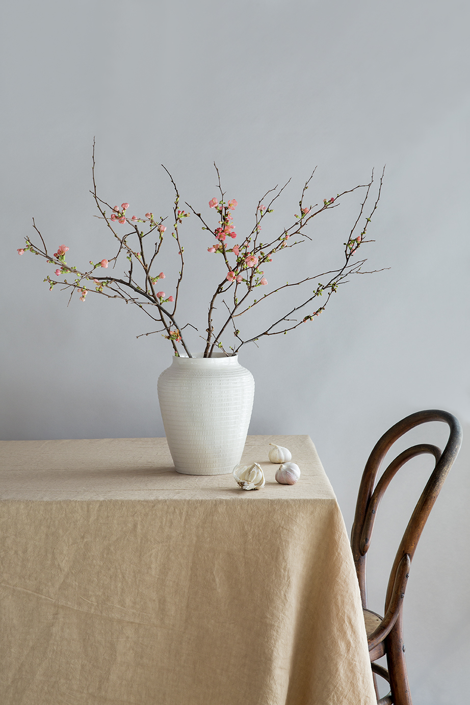 White glazed vase with branches on a table