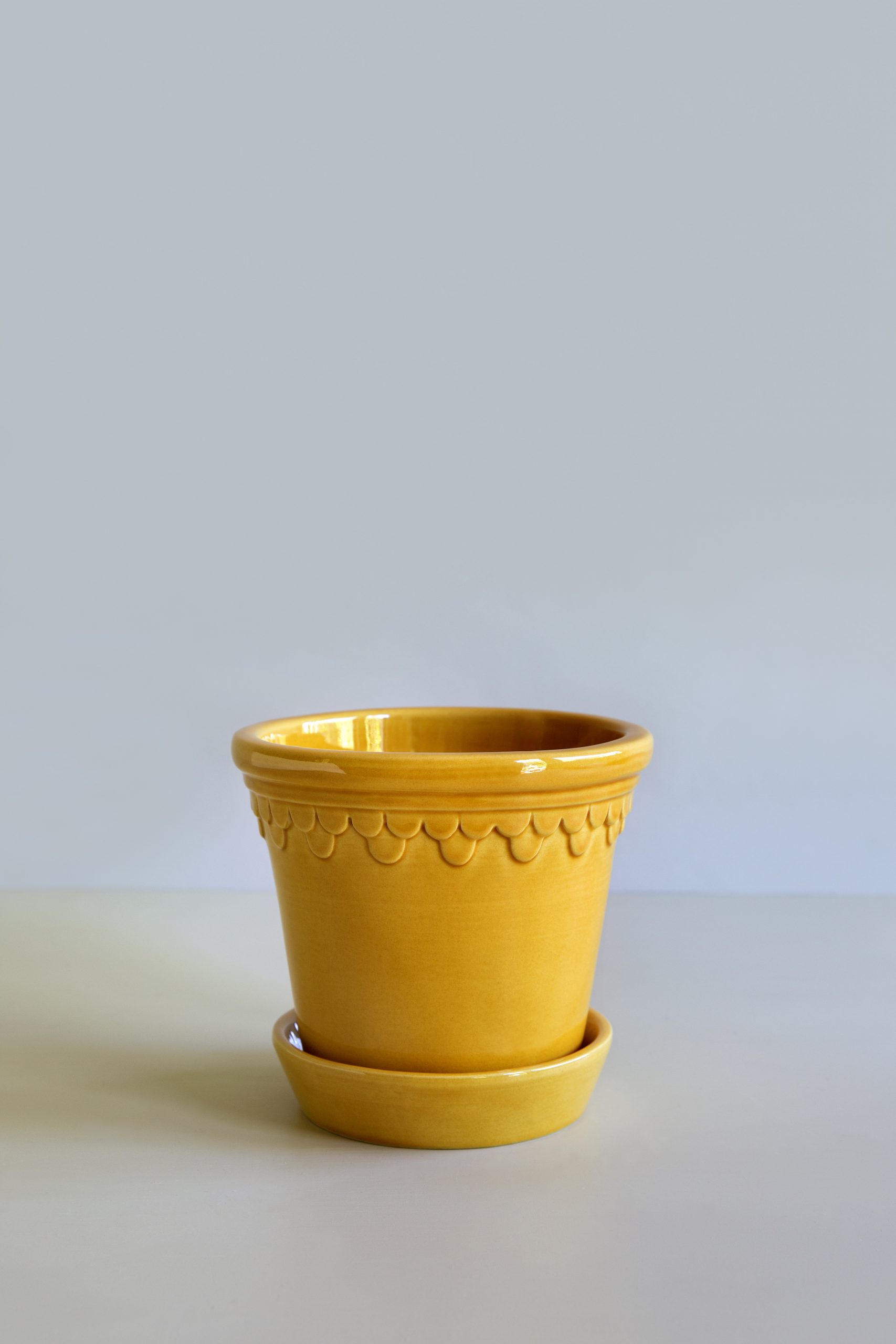 Glazed amber yellow pot with saucer.
