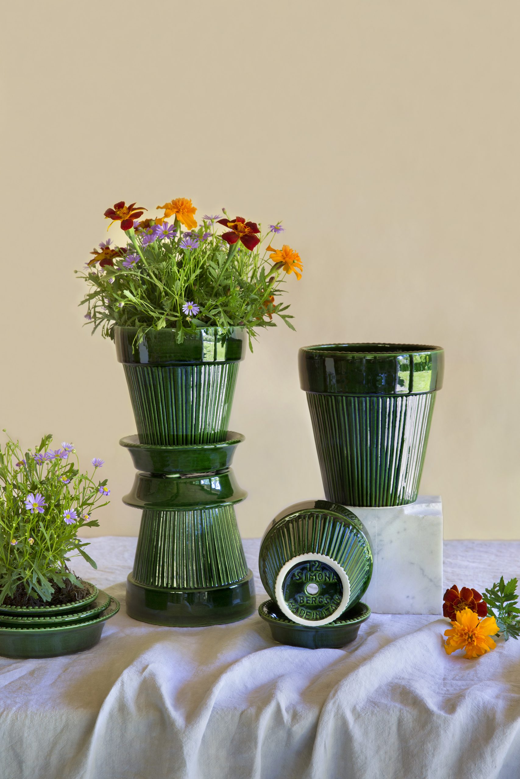 Collection of glazed green pots with flowers.