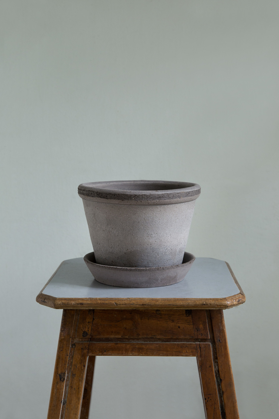 Raw grey pot with saucer on a stool.