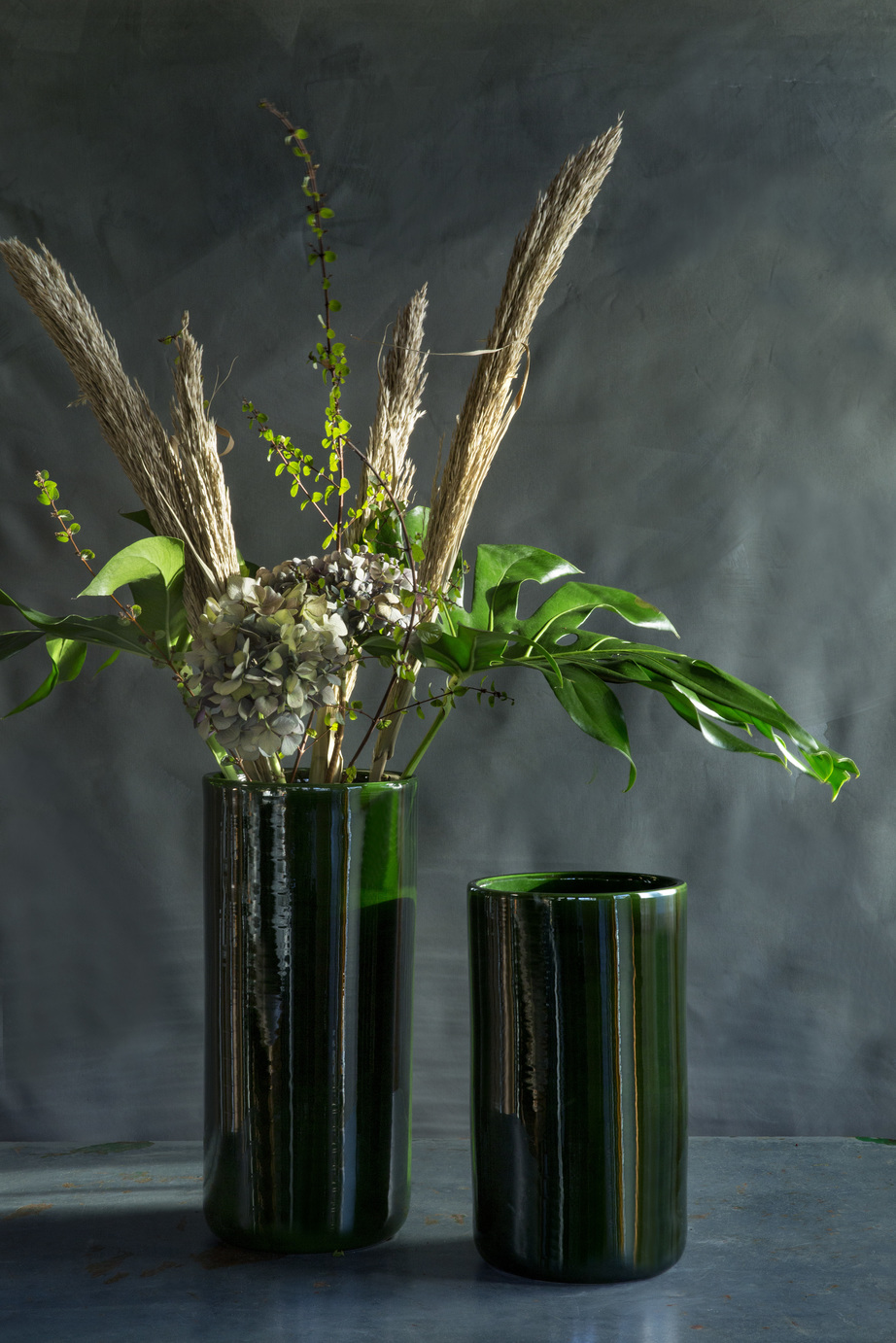 Two simple green glazed floor vases with flowers