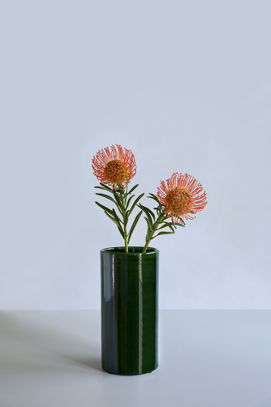 Green glazed vase with orange flowers