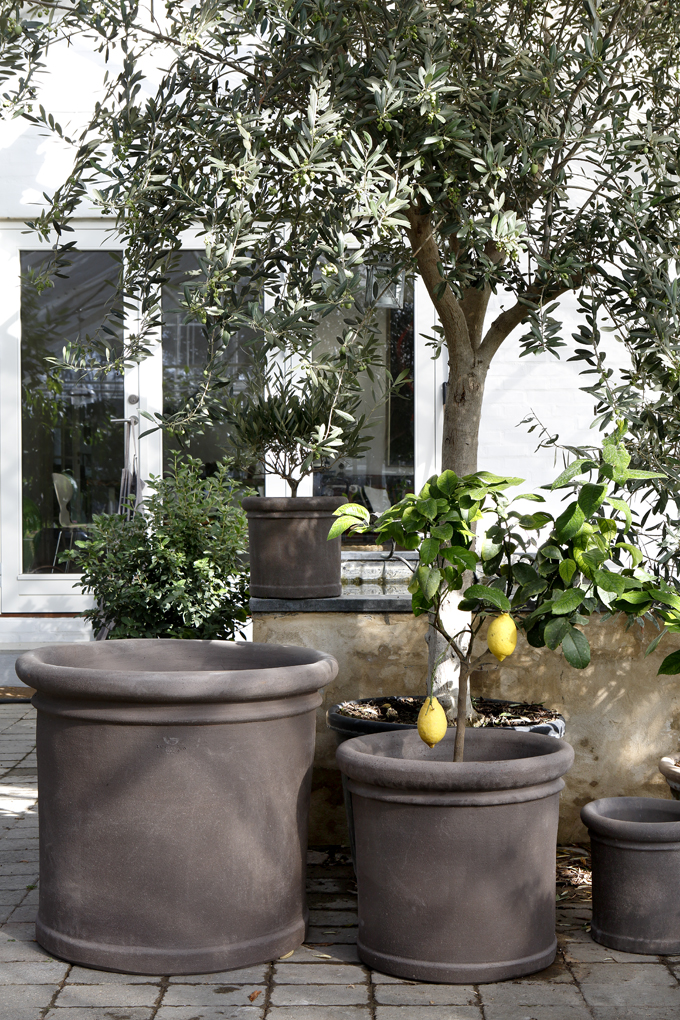 Three different sized cylindrical raw grey outdoor pots.