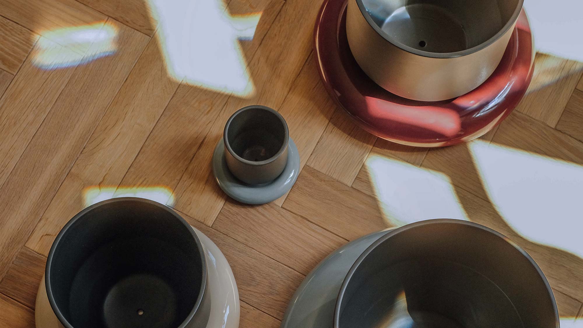 Assorted Bergs Potter Lily pots with colorful glazed saucers on wooden floor