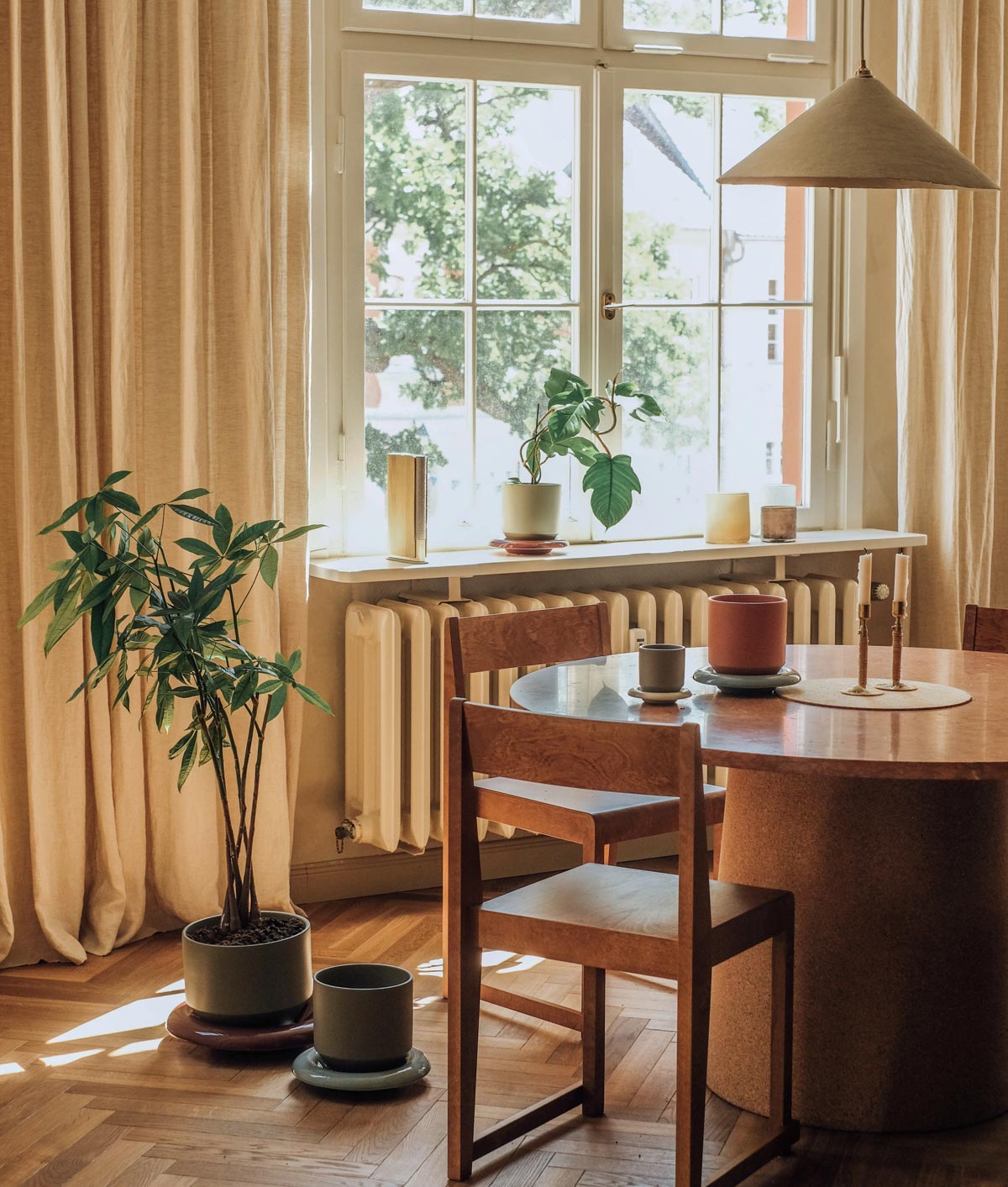 Lily pots and saucers in different colours by Bergs Potter, styled on a wooden dining table
