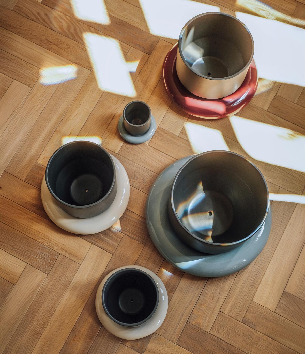 Assorted Lily pots and saucers in muted colors on wooden floor