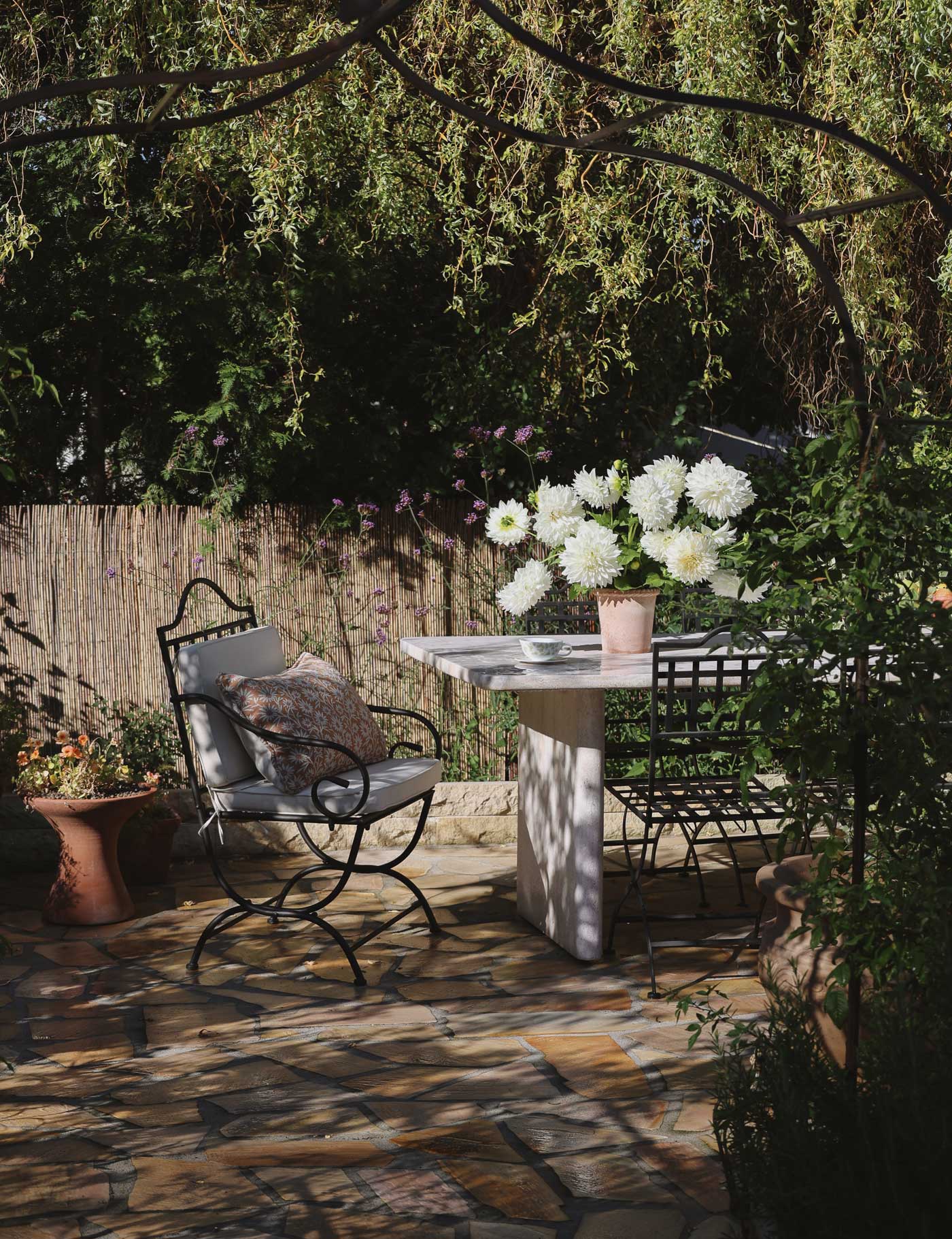 Emilia pot in Rosa terracotta filled with white dahlias, styled on an outdoor garden table in the sunlight.
